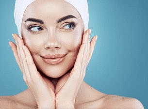 Smiling woman with flawless skin, hands on face.