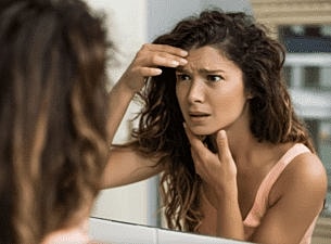 Smiling woman with healthy skin and makeup.