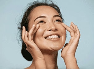 Woman smiling with curly hair and closed eyes.
