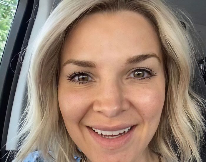 Smiling person with blonde hair in car.