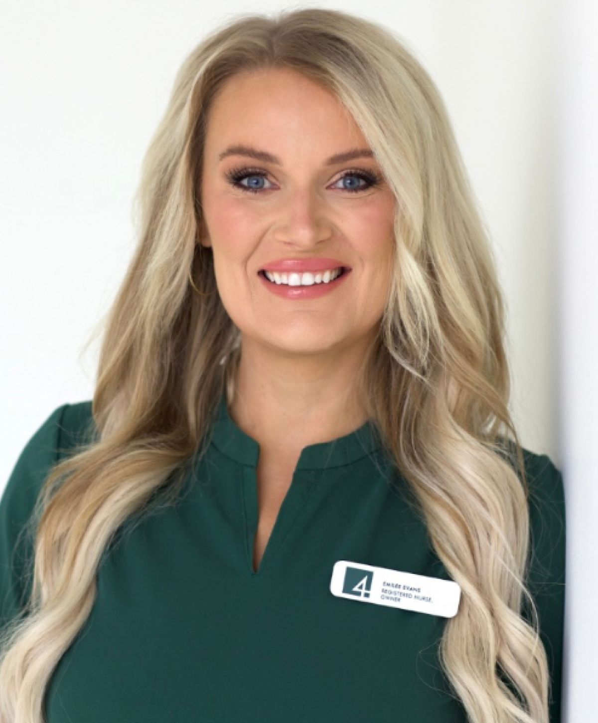 Smiling woman in green attire with name tag.