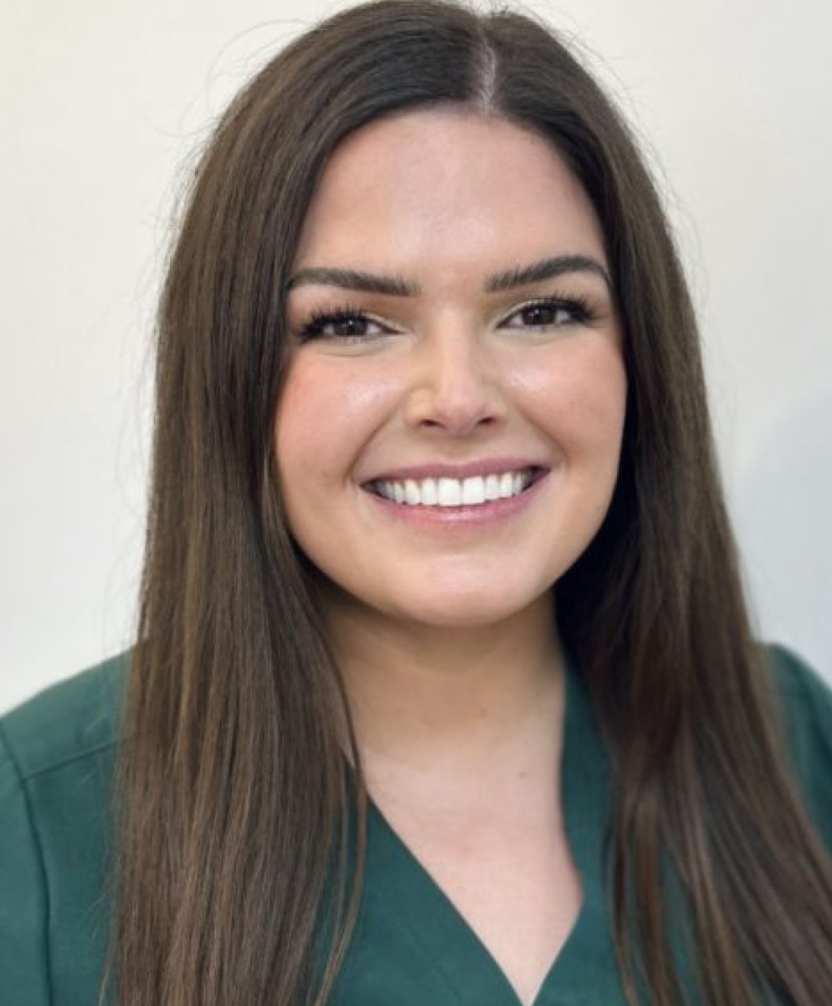 Smiling woman in green attire with long hair.