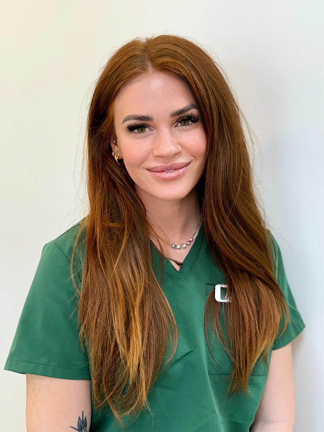 Smiling woman in green medical scrubs.