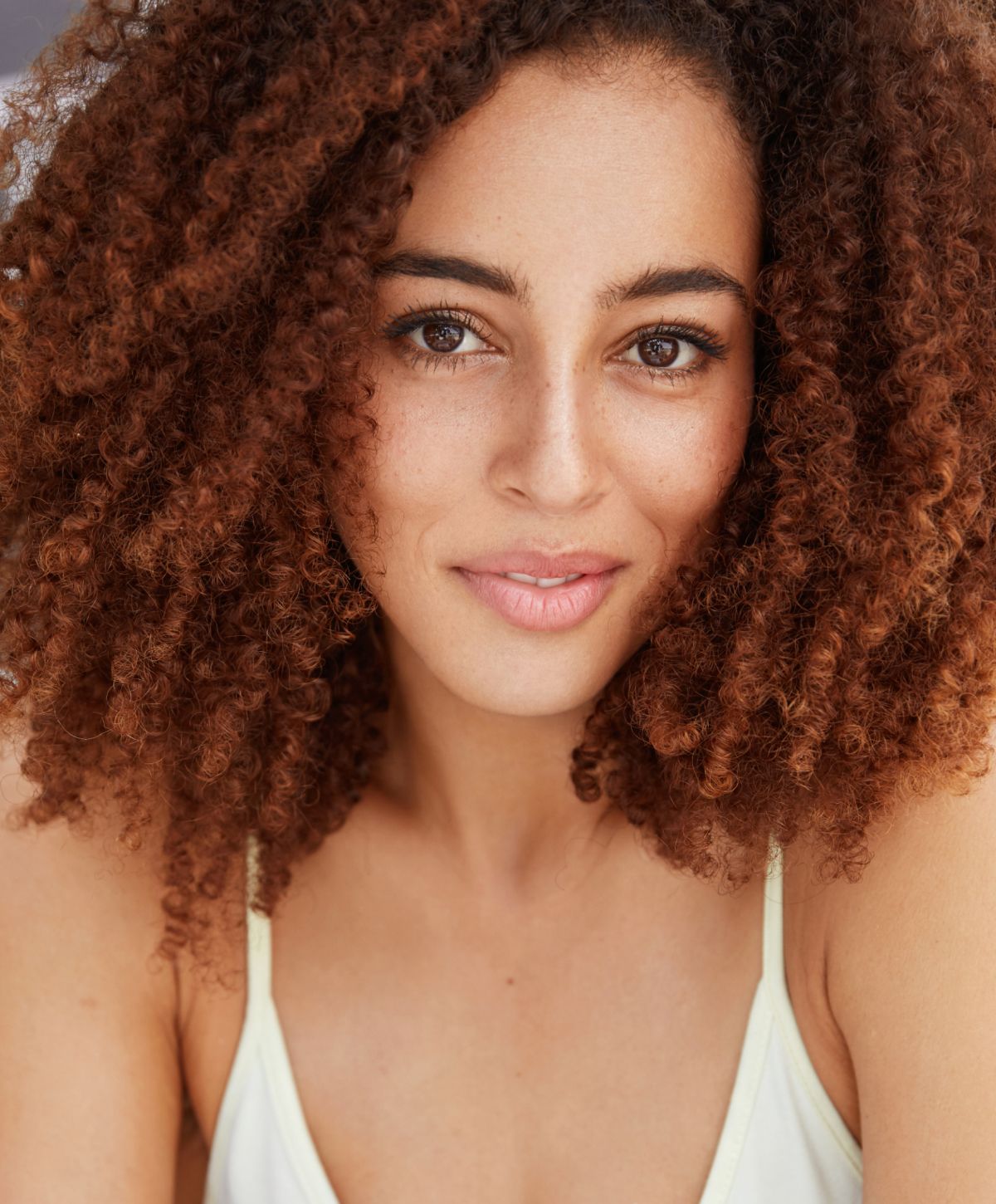 Woman with curly hair and warm smile.