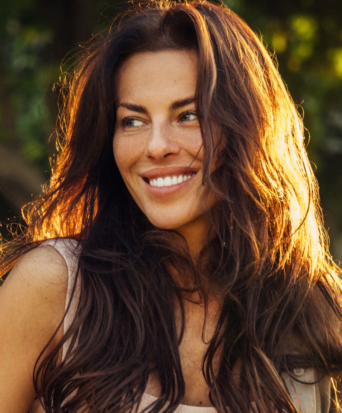 Smiling woman with long, flowing hair outdoors.