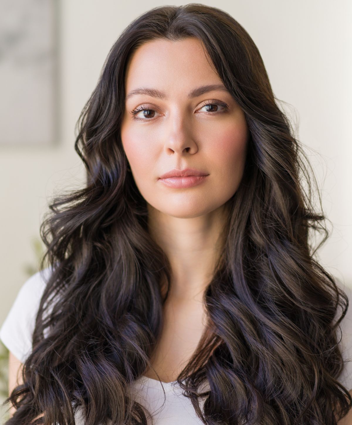 Woman with long, wavy dark hair and natural makeup.