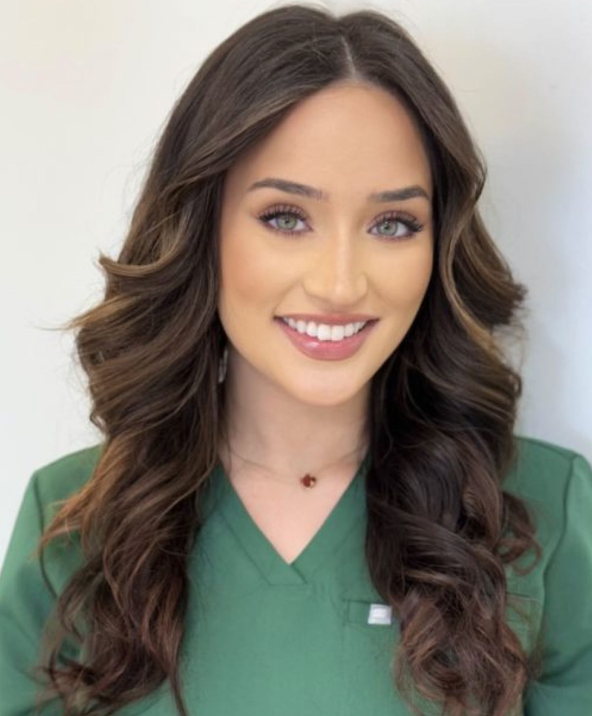 Smiling woman in green scrubs and necklace.