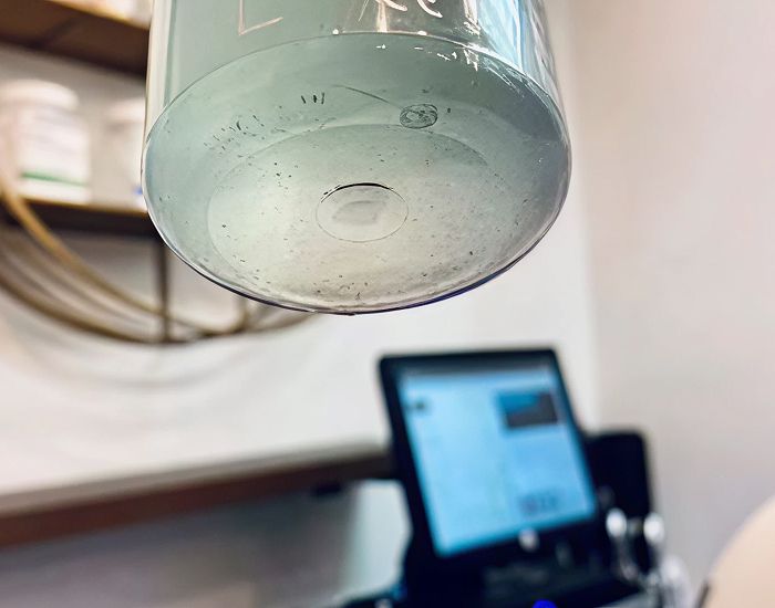 Clear glass cup hanging above a computer.