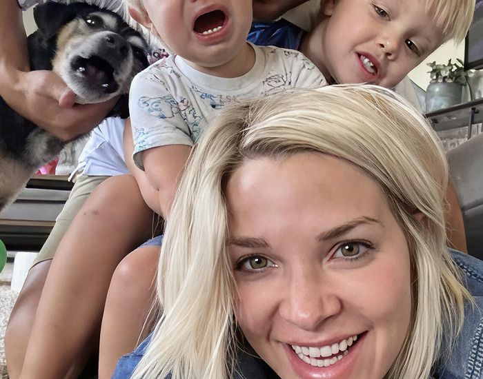 Family smiling together with a dog.