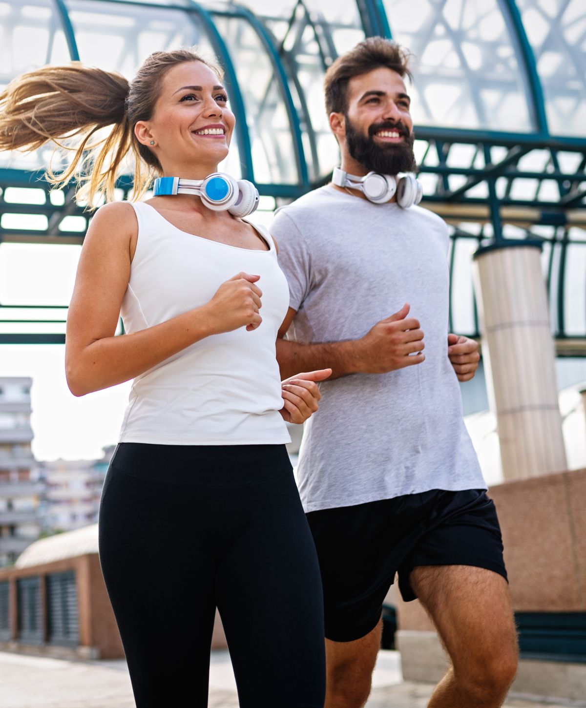 Couple jogging outdoors with headphones on.