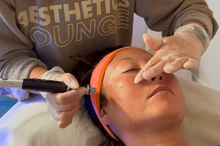 Facial treatment with skincare tools in clinic.