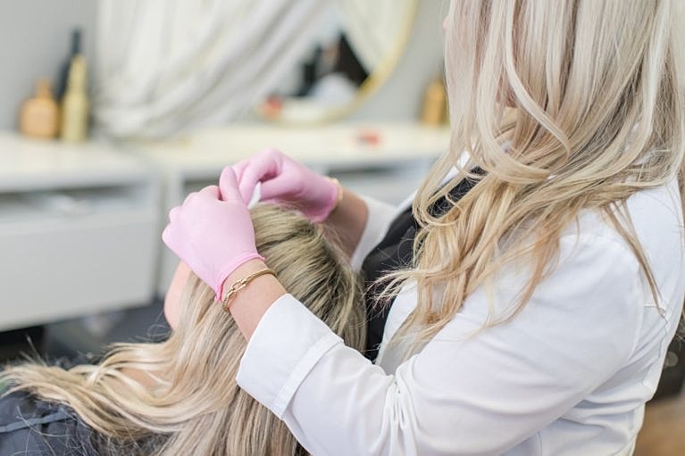 Stylist applying hair treatment in salon setting.