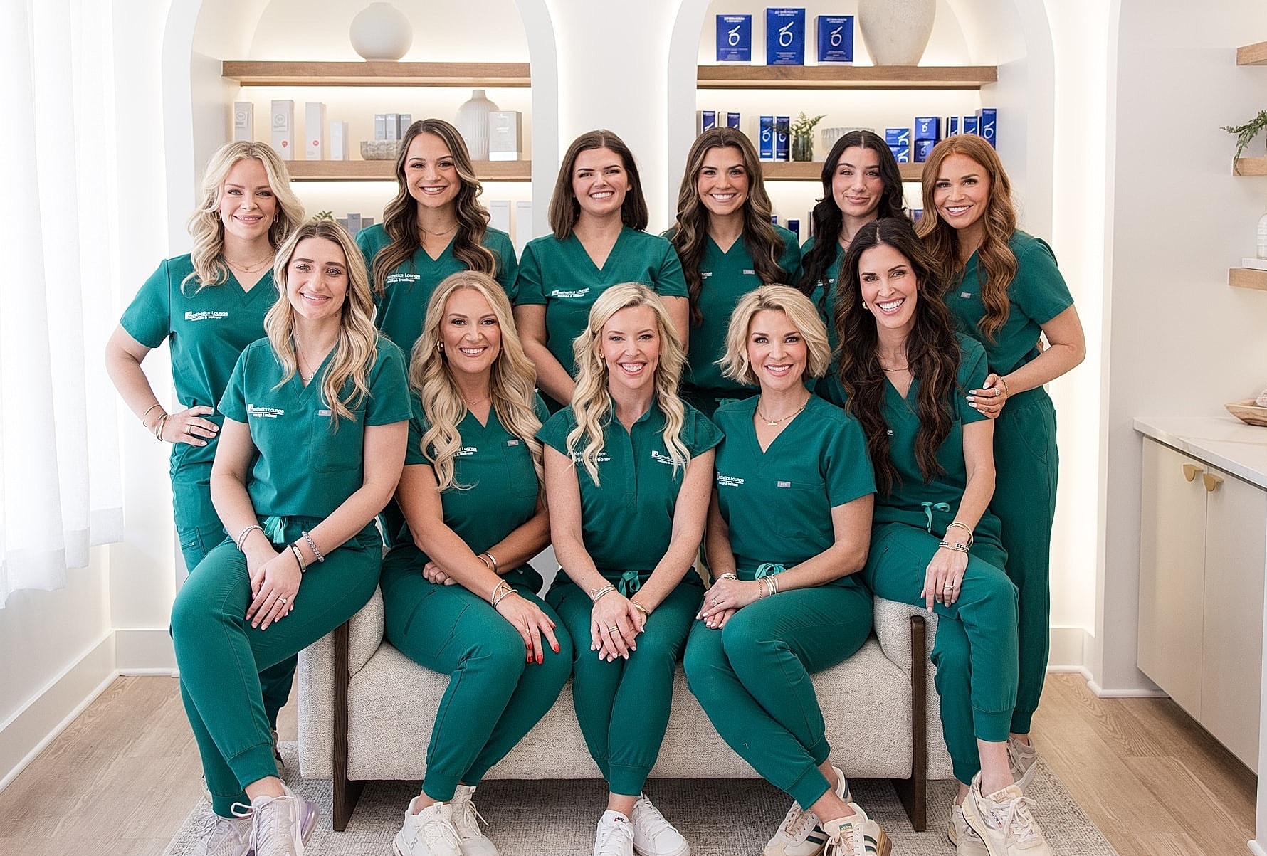 Team of professionals in green scrubs smiling together.