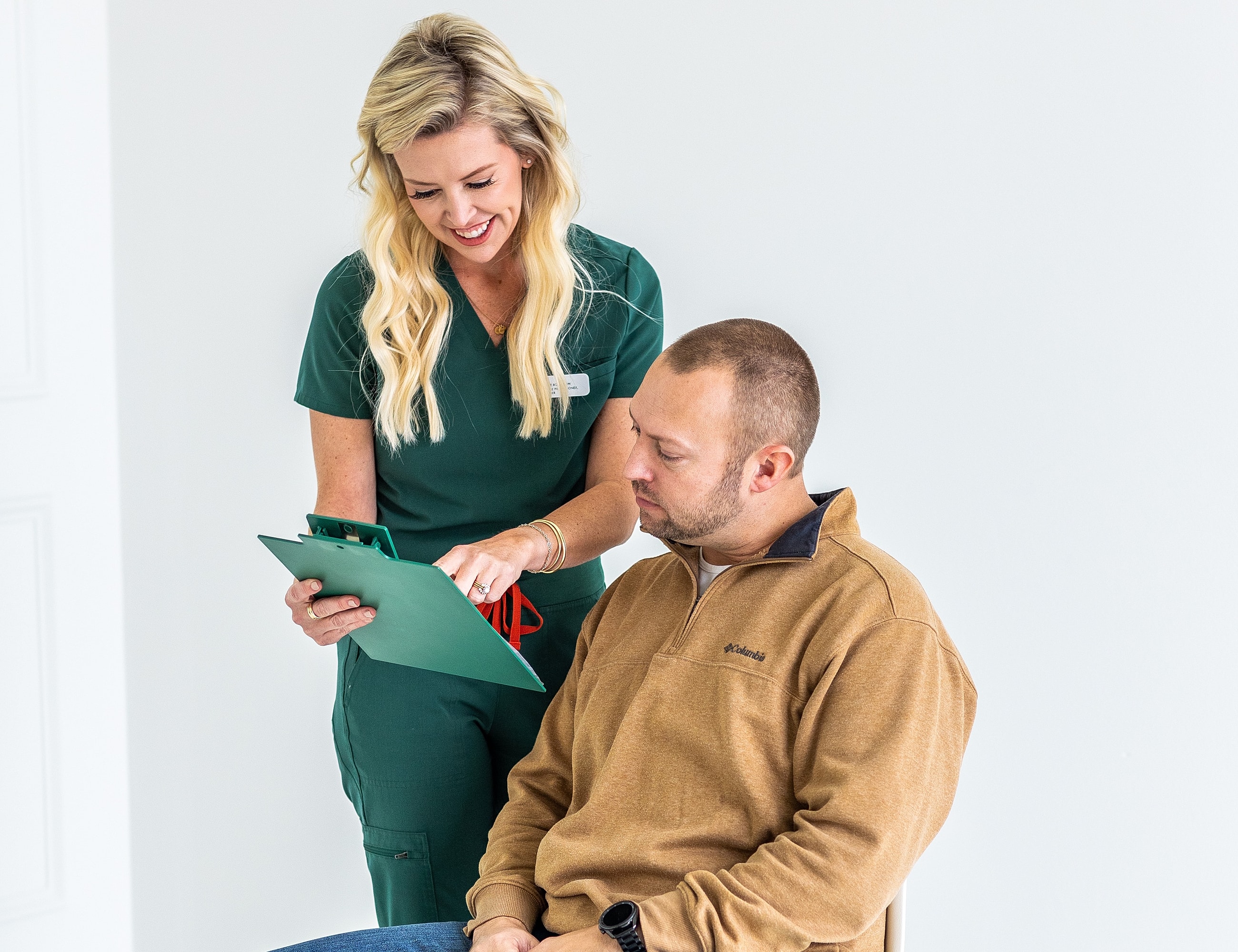Healthcare professional assisting male patient with clipboard.