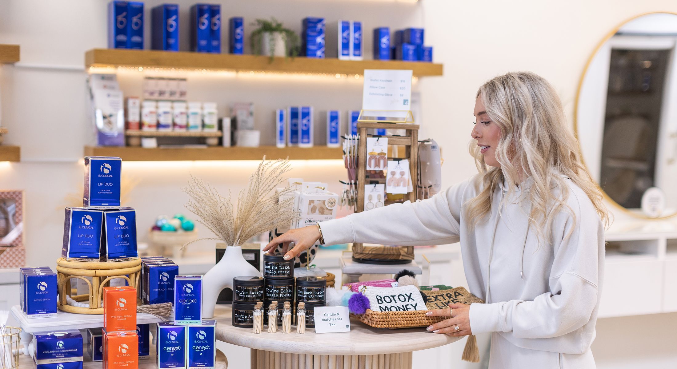 Woman arranging skincare products on display table.
