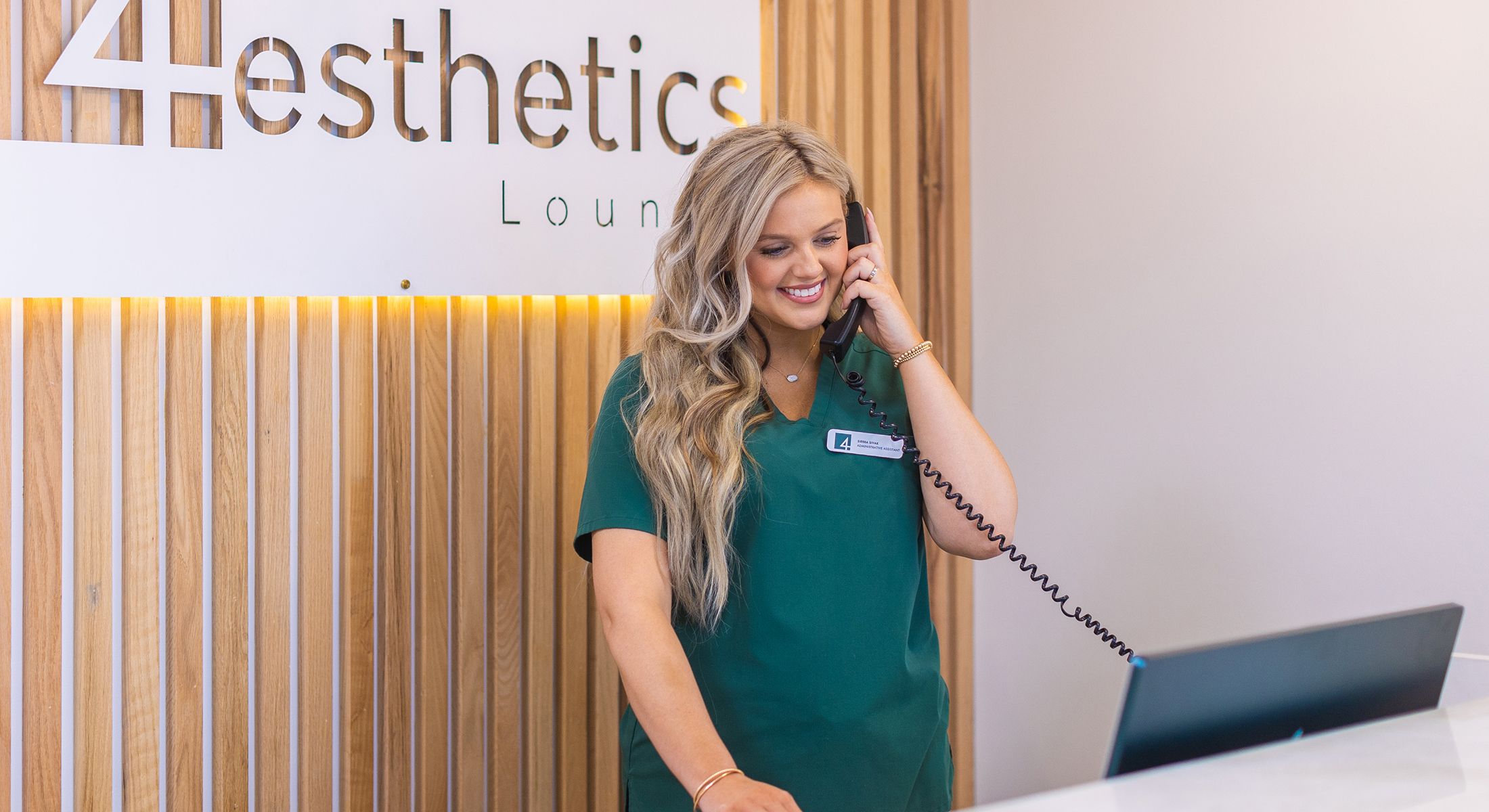 Receptionist on phone at aesthetics lounge.