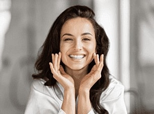 Smiling woman with hands on her face.