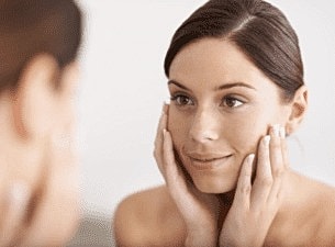 Woman examining her face in the mirror.