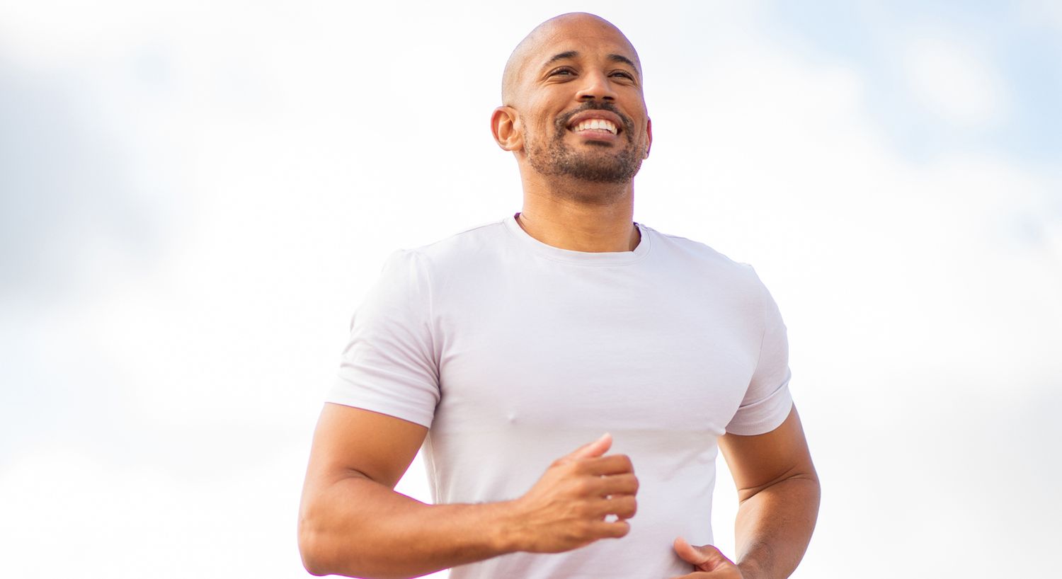Man jogging outdoors with a smiling expression.