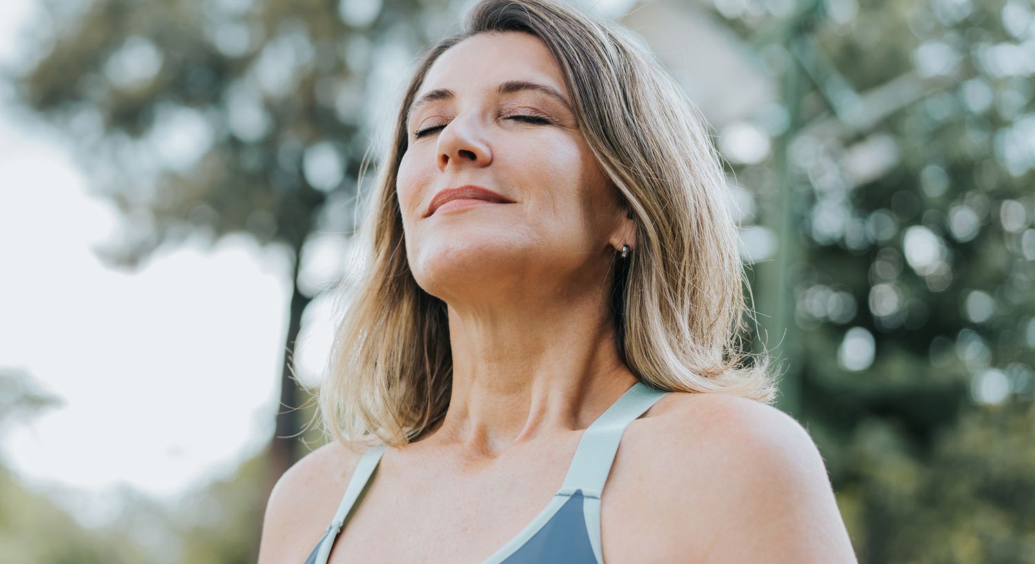 Woman meditating outdoors with a peaceful expression.