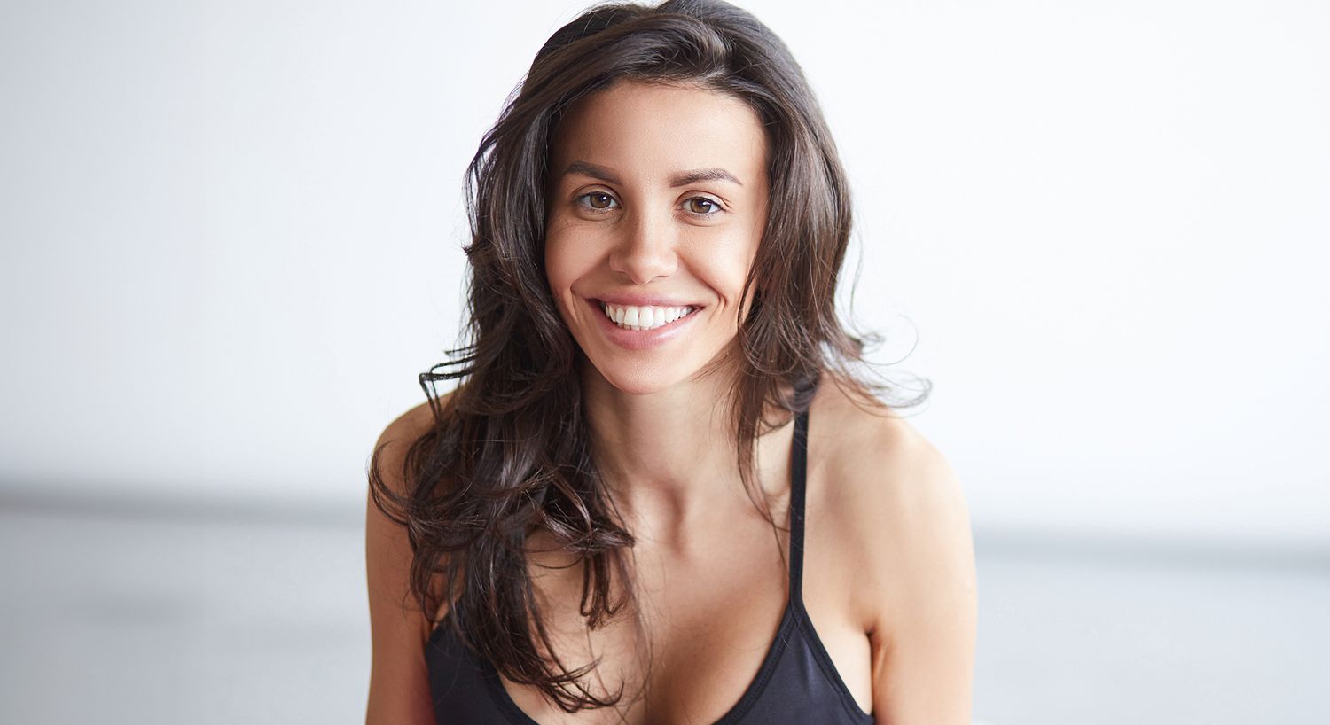 Smiling woman with long, dark hair in tank top.