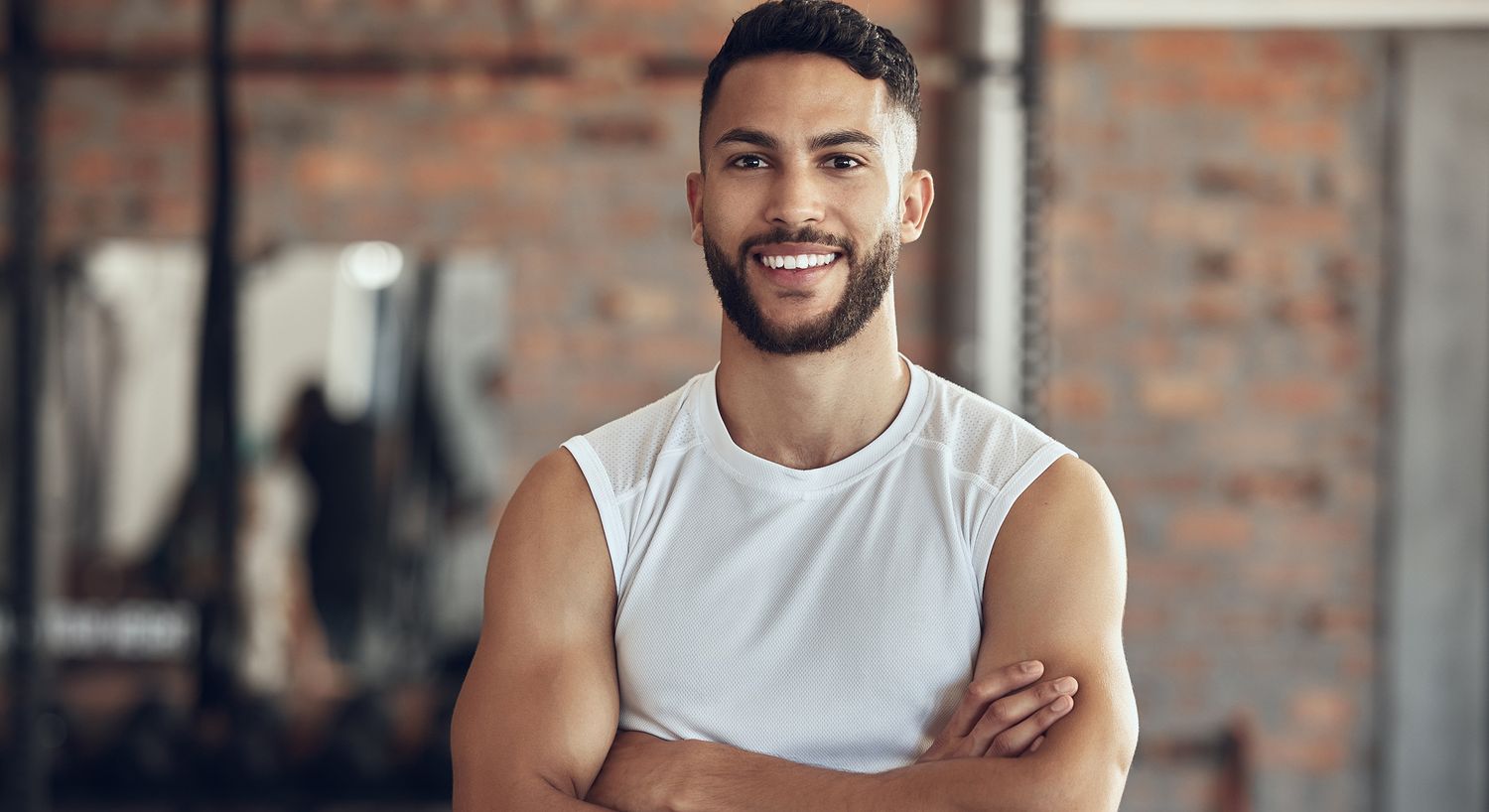 Smiling man in gym attire with crossed arms.